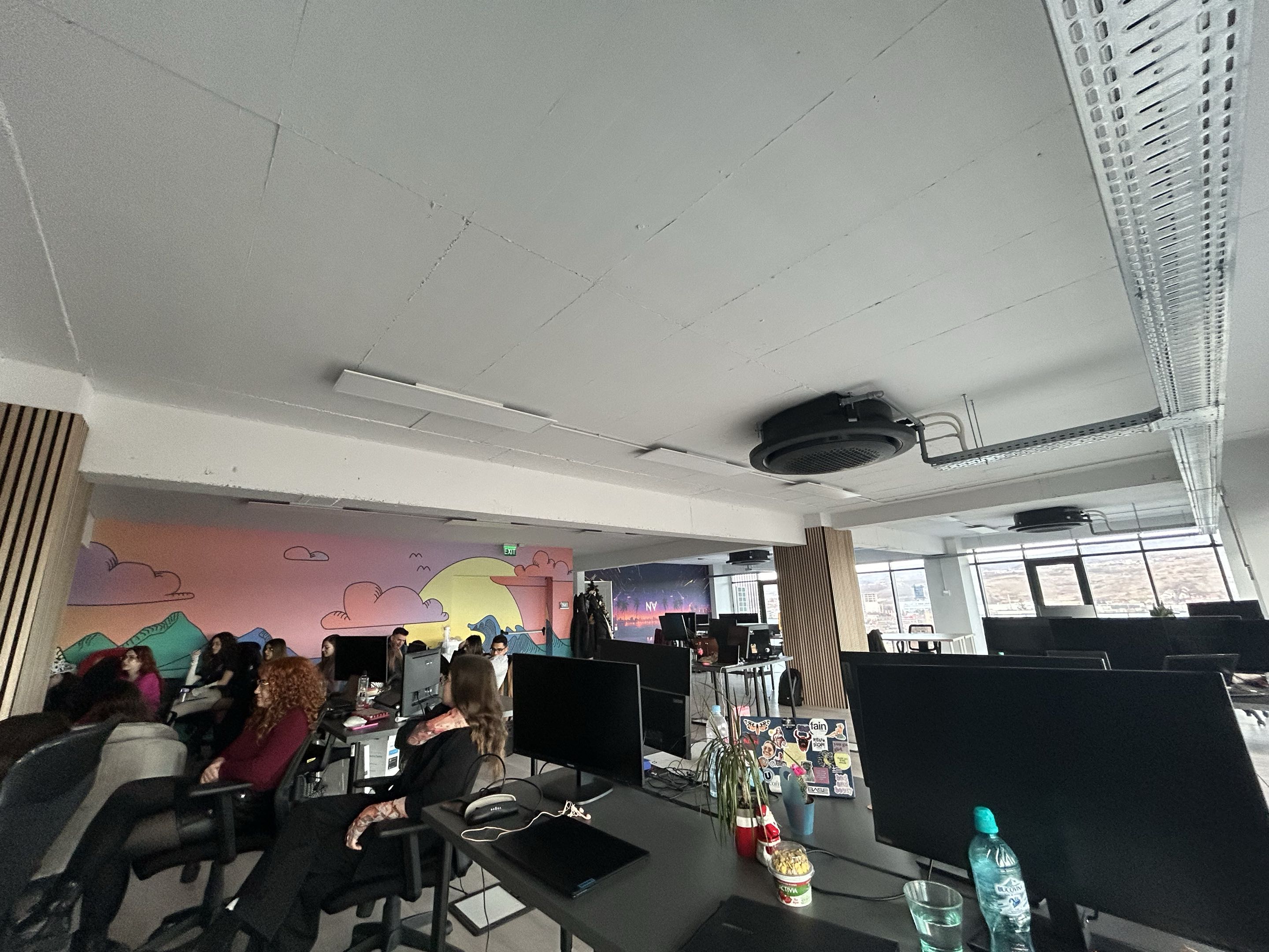 Team working at desks with monitors, mural in background